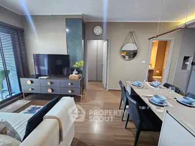Modern living room with stylish decor and dining area, featuring a large TV and elegant furnishings.