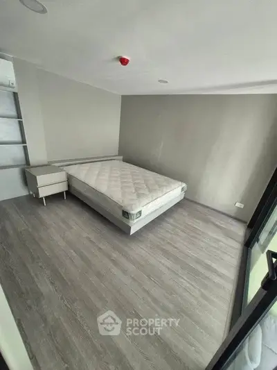 Spacious bedroom with modern flooring and large window for natural light