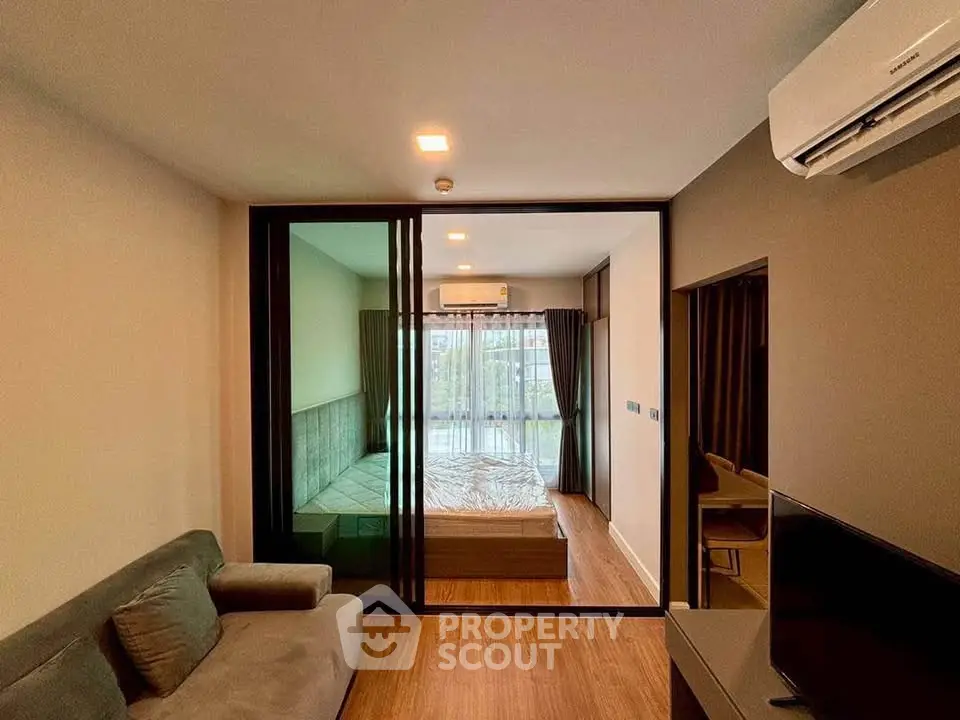 Modern apartment interior with glass partition, cozy living area, and natural light.