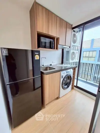 Modern compact kitchen with appliances and balcony view in urban apartment