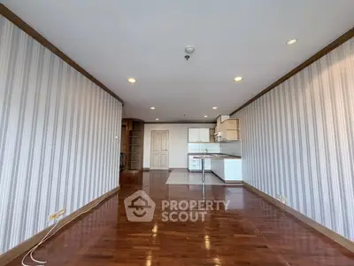 Spacious open-plan living room with wooden flooring and modern kitchen area.