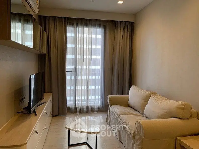 Cozy living room with modern decor and natural light, featuring a comfortable sofa and sleek TV setup.