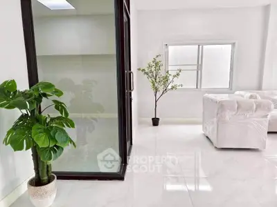 Bright modern living room with large windows and elegant white furnishings.