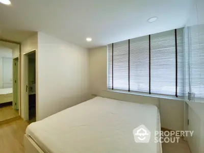 Spacious bedroom with large windows and modern decor in a stylish apartment.