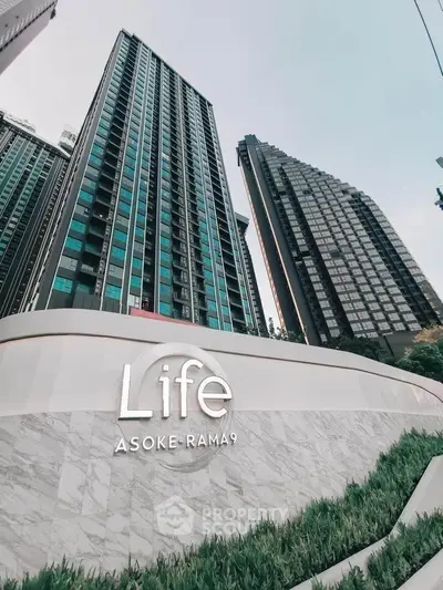 Modern high-rise condominium Life Asoke-Rama 9 with sleek architecture and lush landscaping.
