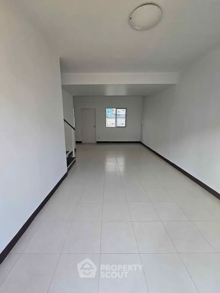 Spacious empty room with tiled flooring and natural light, ideal for customization.