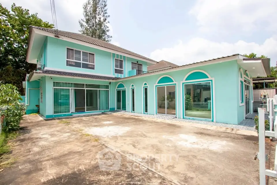 Spacious modern turquoise house with large windows and driveway