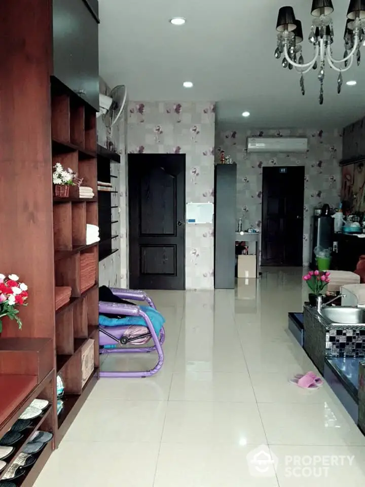 Elegant interior with glossy tiled flooring, wooden shelving, and a chic chandelier complementing the floral wallpaper, creating a modern yet cozy ambiance.