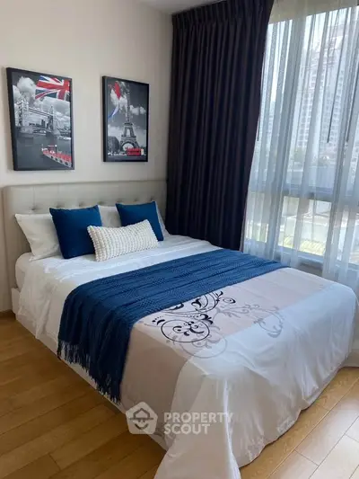 Modern bedroom with stylish decor and large window offering city views.