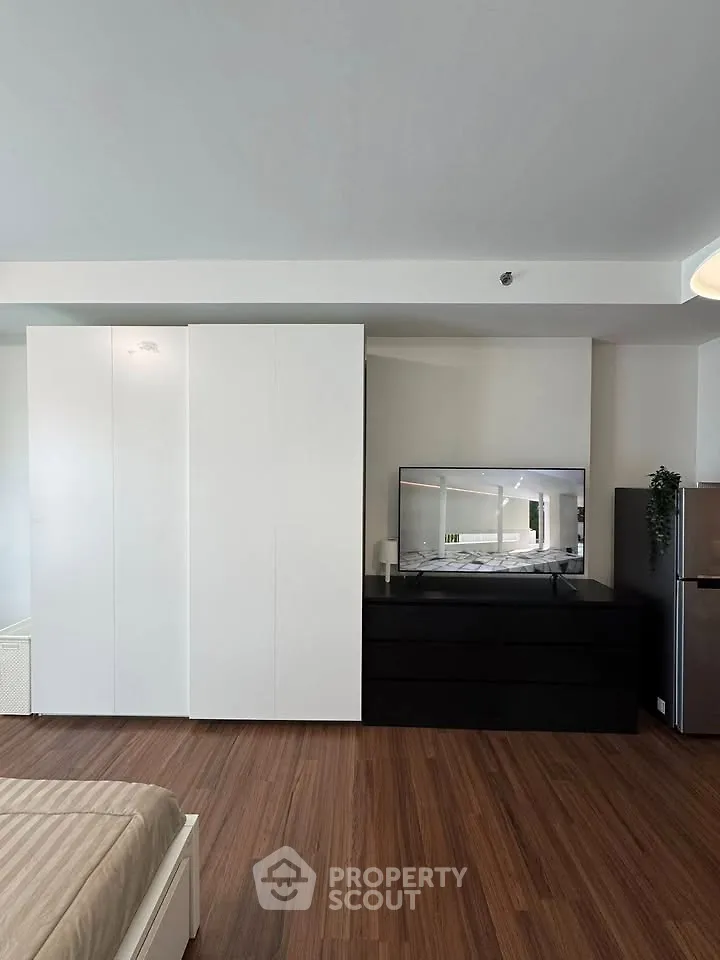 Modern bedroom with sleek wardrobe and TV on wooden flooring