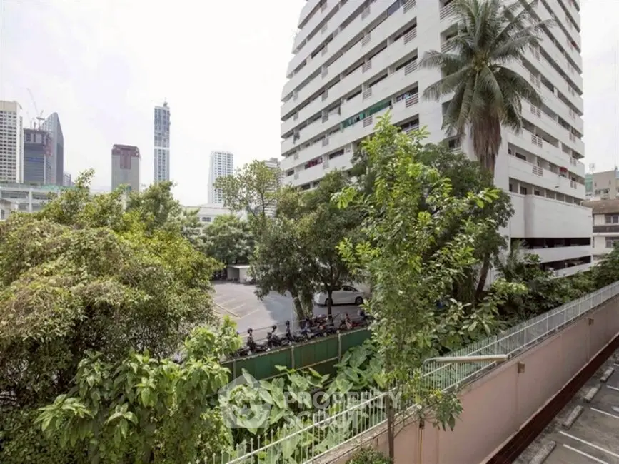 Urban residential building with lush greenery and city skyline view.