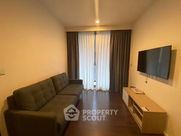 Modern living room with sleek sofa and wall-mounted TV, featuring elegant curtains and wooden flooring.