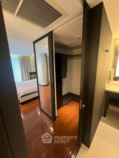 Spacious bedroom with walk-in closet and modern design, featuring wooden flooring and ample natural light.