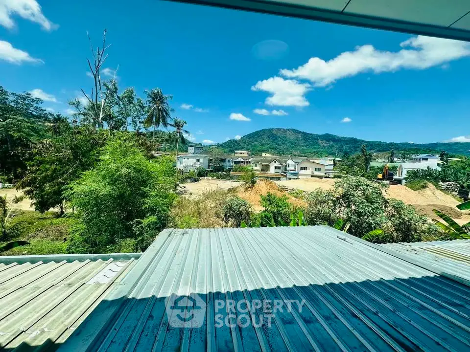 Scenic view from a rooftop overlooking lush greenery and distant mountains, perfect for nature lovers.