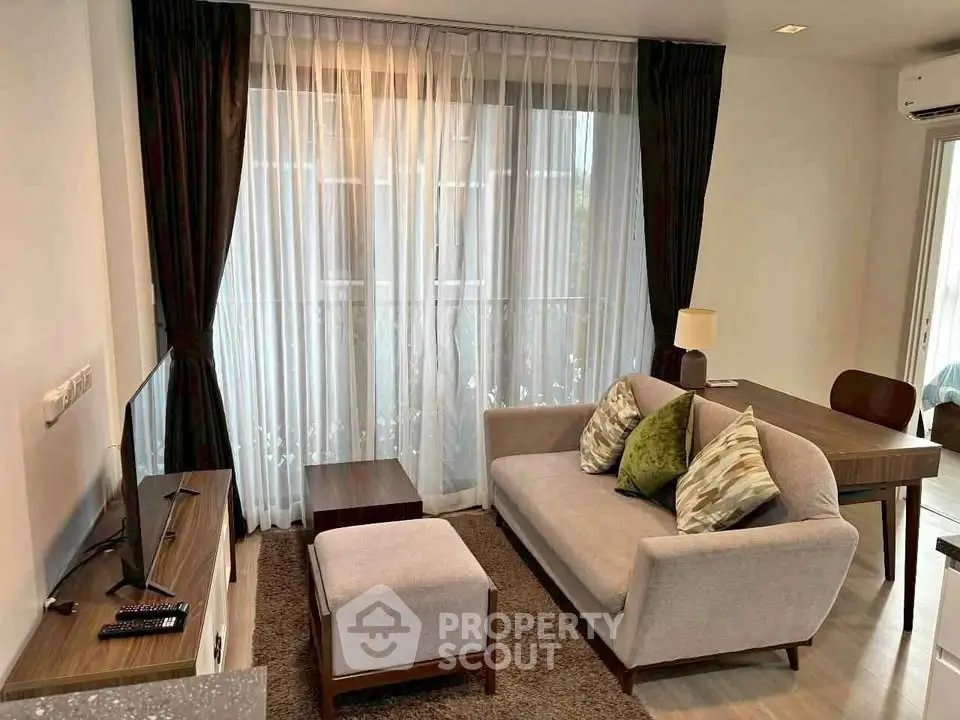 Cozy living room with modern furniture and large window with sheer curtains.