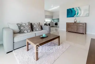 Modern living room with stylish decor and open kitchen layout, featuring a cozy sofa and elegant artwork.