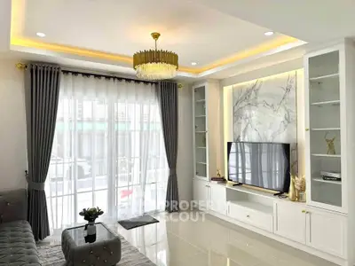 Elegant living room with modern decor, large windows, and stylish chandelier.