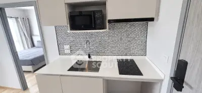Modern kitchen with sleek design, featuring a compact layout, built-in microwave, and stylish backsplash.