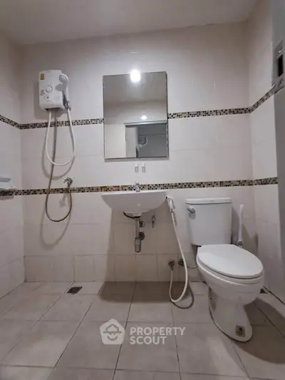 Modern bathroom with shower, sink, and toilet in a tiled setting.