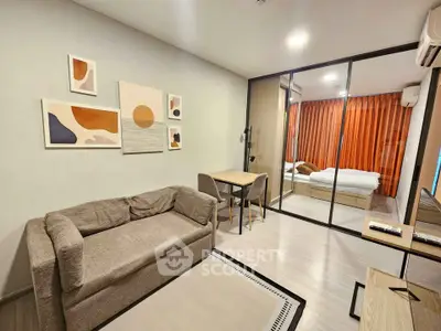 Modern living room with cozy sofa and stylish decor, adjacent to a bedroom with glass partition.