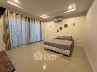 Spacious bedroom with modern decor and large windows for natural light.