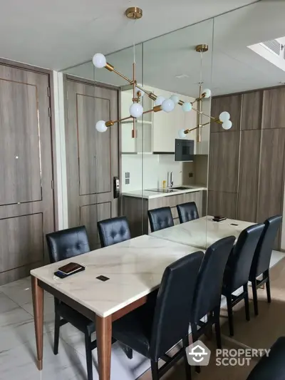 Modern dining area with elegant chandelier and mirrored wall in luxury apartment