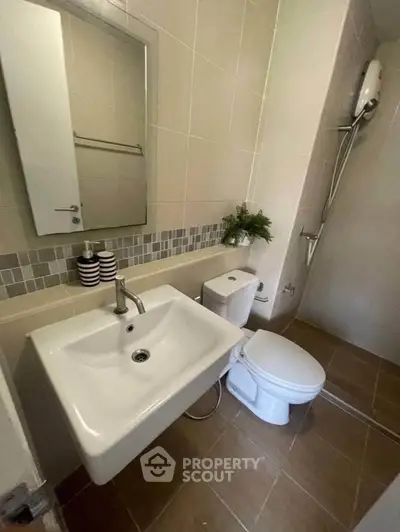 Modern bathroom with sleek fixtures and neutral tiles, featuring a shower and stylish sink.
