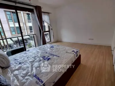 Spacious bedroom with large windows and modern design in urban apartment.