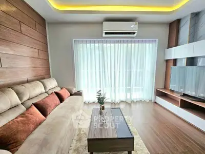 Modern living room with stylish decor, large sofa, and natural light through sheer curtains.