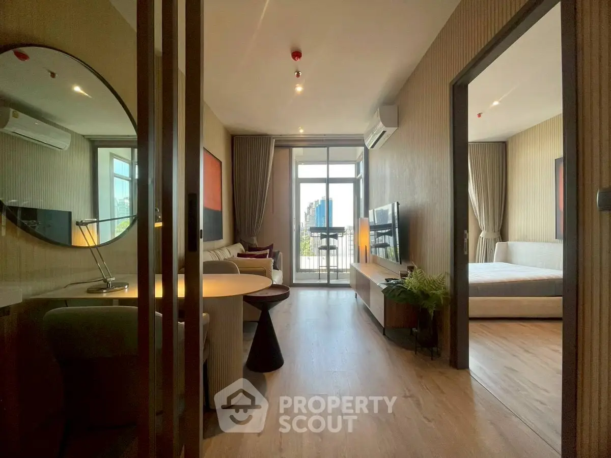 Modern apartment interior with open living room and bedroom, featuring stylish decor and city view balcony.