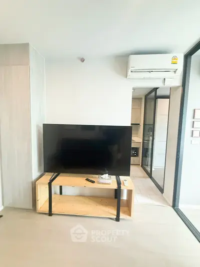 Modern living room with sleek TV setup and air conditioning in a stylish apartment.