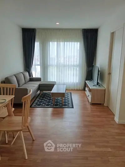 Modern living room with cozy sofa, TV, and dining area in bright apartment.