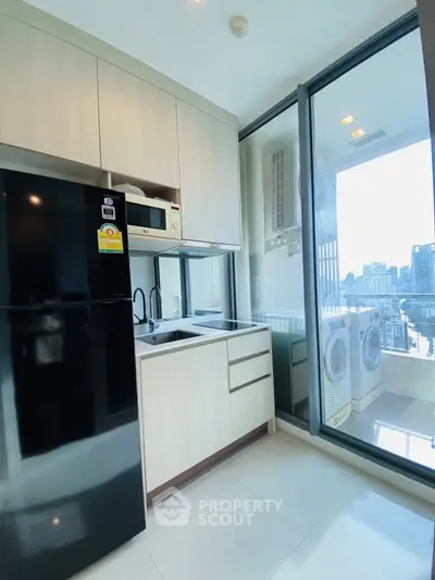 Modern kitchen with sleek appliances and balcony view in high-rise apartment