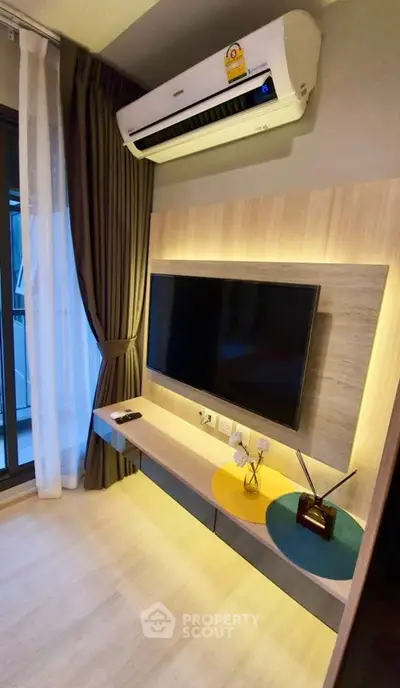 Modern living room with wall-mounted TV and air conditioning, featuring stylish decor and natural lighting.