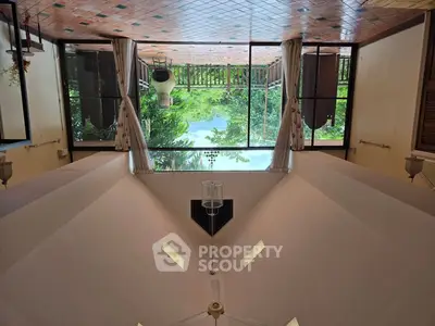 Spacious living room with large windows offering a stunning garden view.