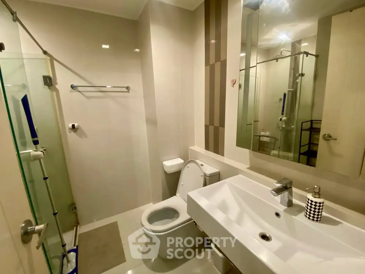 Modern bathroom with glass shower and sleek fixtures in a contemporary apartment.