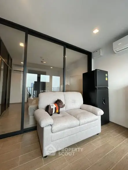 Modern living room with cozy sofa and sleek black refrigerator in a stylish apartment.
