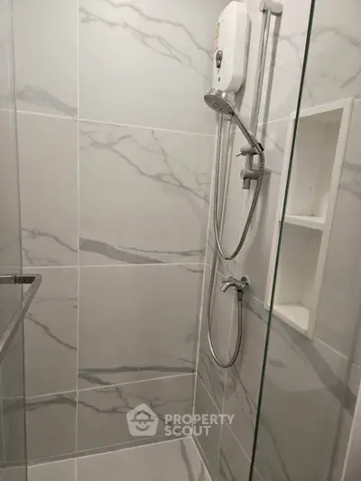 Modern bathroom with sleek marble tiles and a glass shower enclosure.