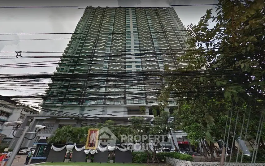 High-rise residential building with lush greenery and street view.