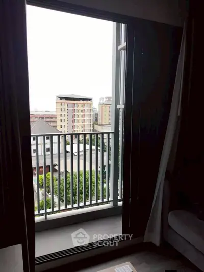 City view from a modern apartment balcony with sliding glass doors.