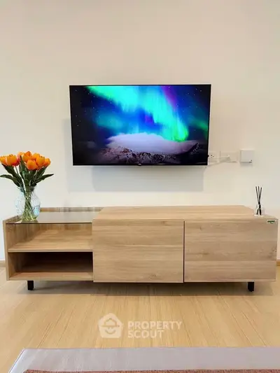 Modern living room with sleek wooden TV stand and vibrant wall-mounted screen displaying aurora borealis.
