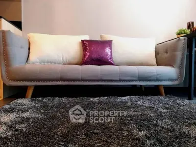 Modern living room with stylish gray sofa and plush rug, perfect for cozy relaxation.