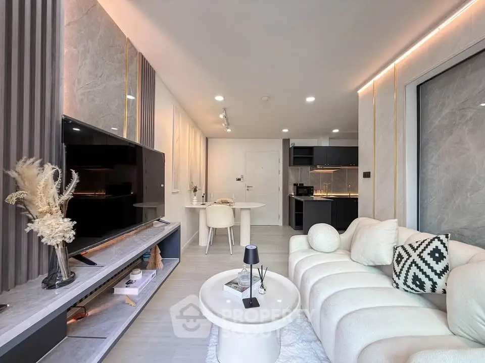 Modern living room with elegant decor and open kitchen layout, featuring stylish furniture and ambient lighting.
