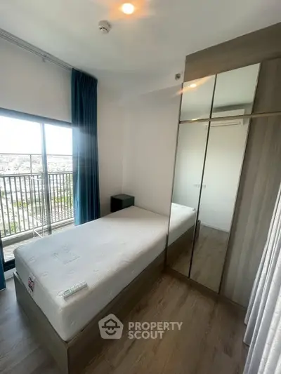 Modern bedroom with large window and mirrored wardrobe in high-rise apartment.