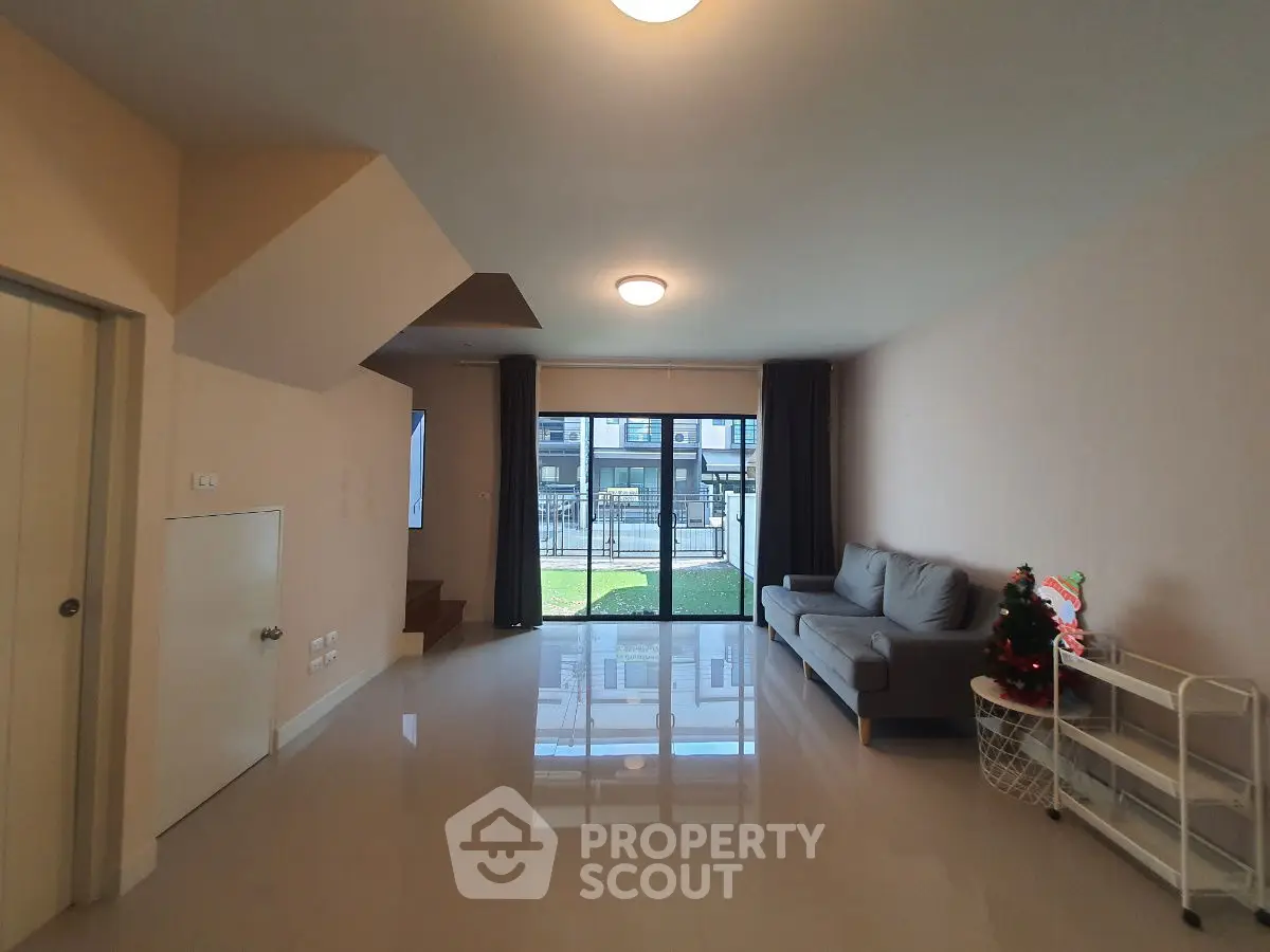 Spacious living room with modern sofa and Christmas decor, featuring large windows and glossy floors.