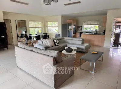 Spacious open-plan living room with modern kitchen and dining area, featuring stylish furniture and natural light.
