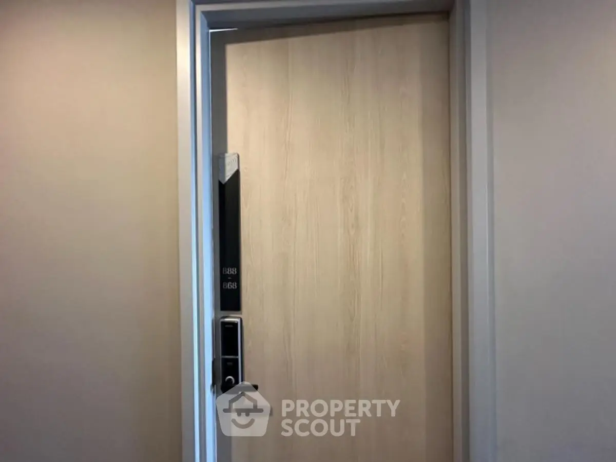 Modern apartment door with electronic lock and room number, showcasing secure and stylish entryway.