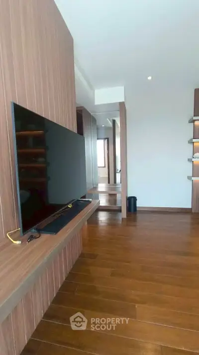 Modern living room with wooden flooring and sleek TV setup in a stylish apartment.
