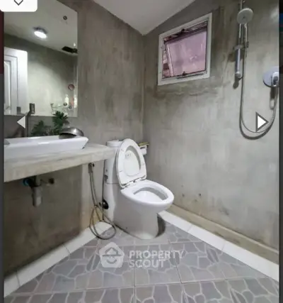 Modern bathroom with concrete walls, stylish fixtures, and geometric tile flooring.