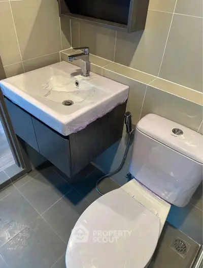 Modern bathroom with sleek fixtures and contemporary design, featuring a stylish sink and toilet.